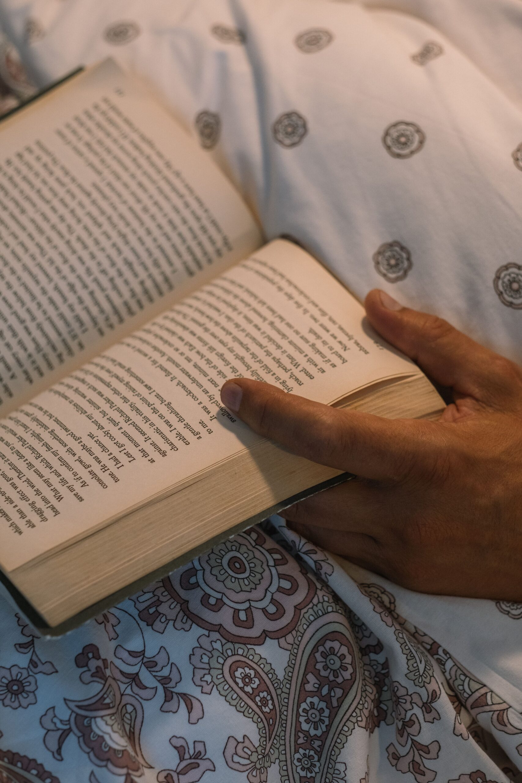 Pessoa lendo um livro em um quarto aconchegante com luz suave antes de dormir, sem telas