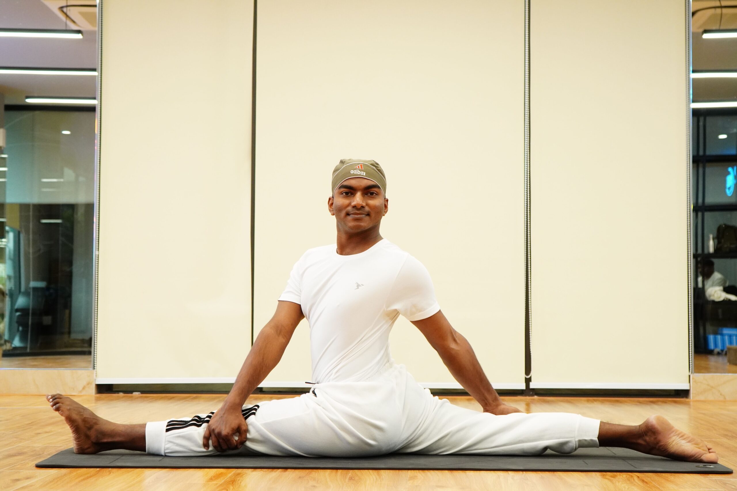 Homem alongando as pernas sobre um tapete de yoga