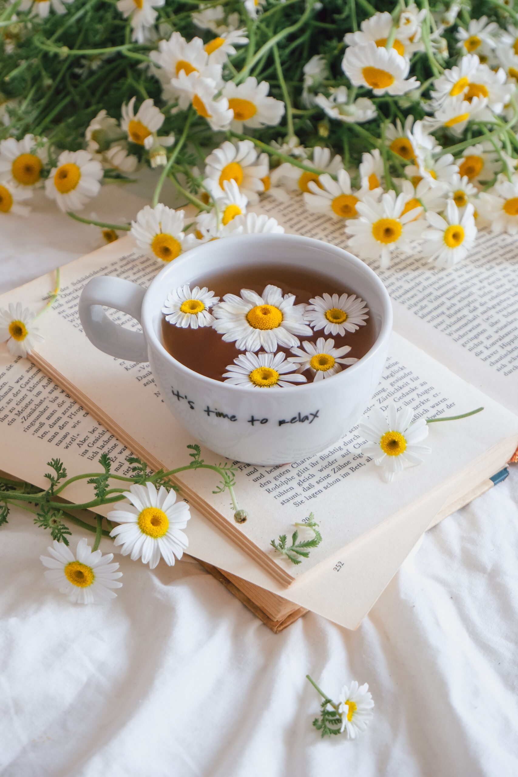 Xícara de chá de camomila com flores ao lado
