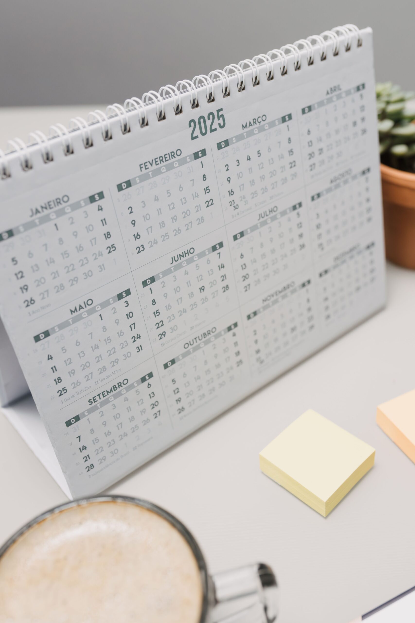 Calendário de mesa com xícara de café e notas adesivas