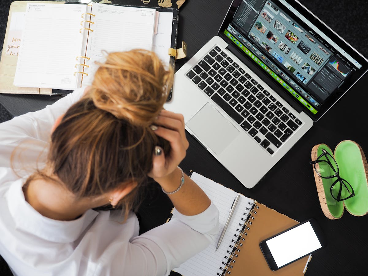 Pessoa em frente ao laptop com expressão de cansaço diante das tarefas