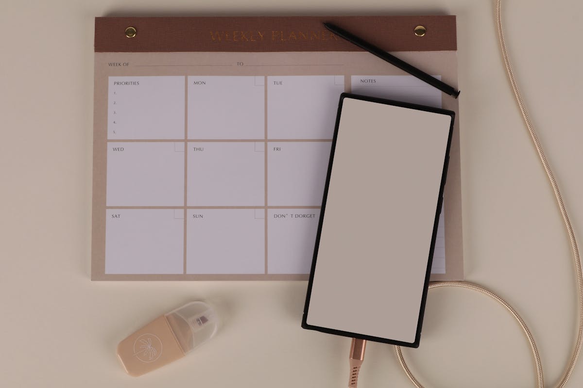 Mesa organizada com planner semanal, celular e materiais de planejamento