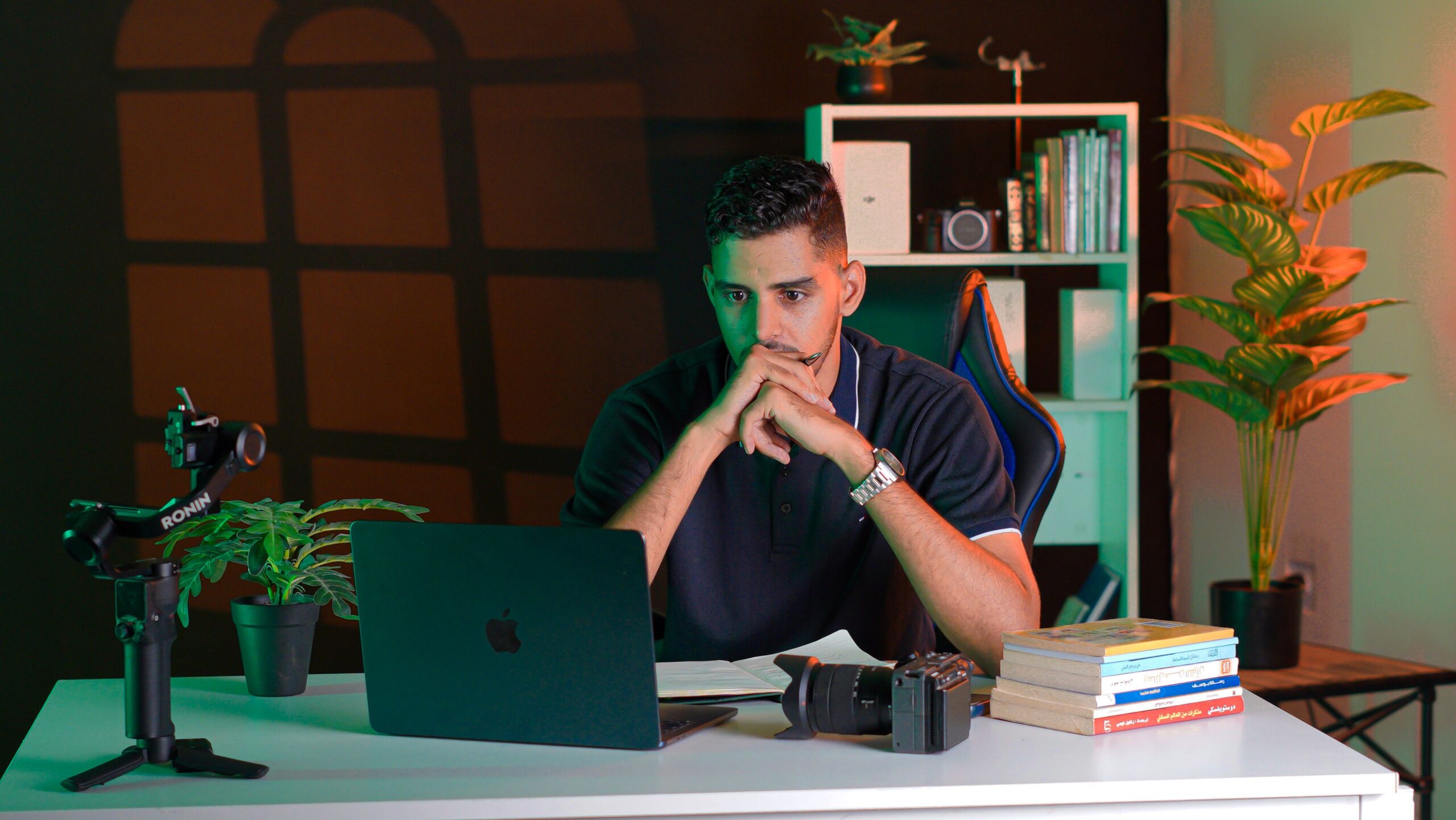 Homem concentrado trabalhando em uma mesa com laptop e livros