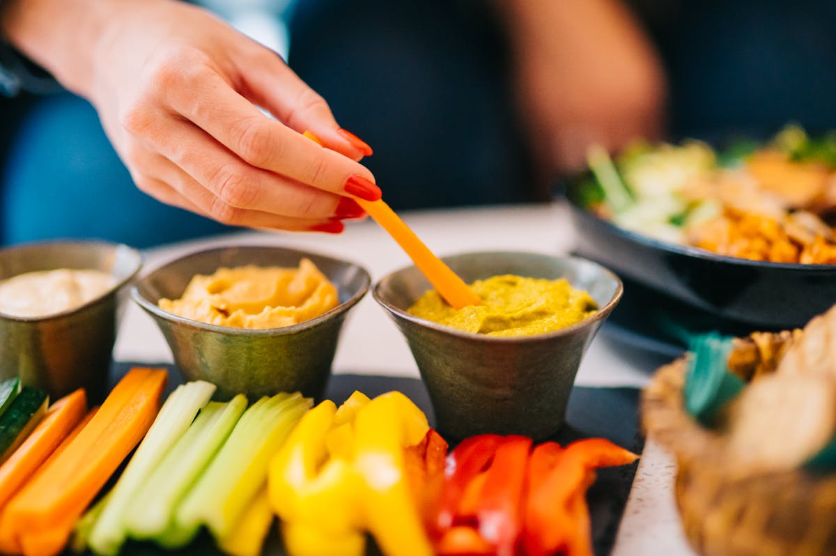 Prato colorido de palitos de vegetais com homus, lanche salgado e saudável