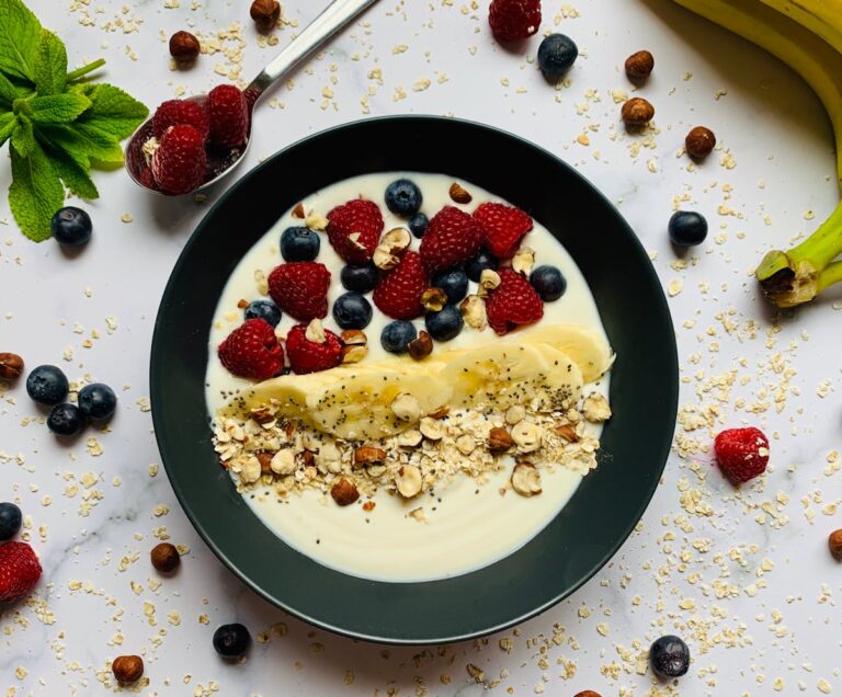 Tigela de café da manhã saudável com iogurte, aveia, frutas vermelhas, banana e castanhas