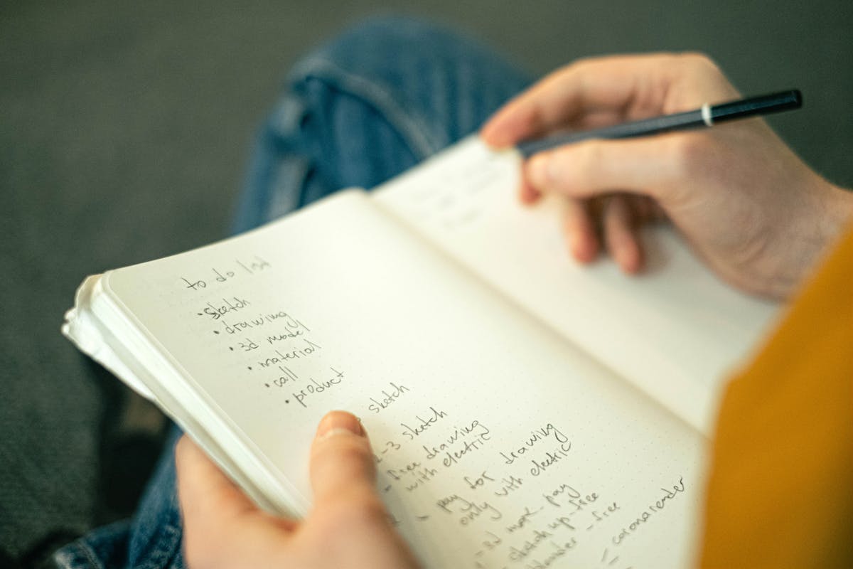 Pessoa escrevendo uma lista de tarefas em um caderno