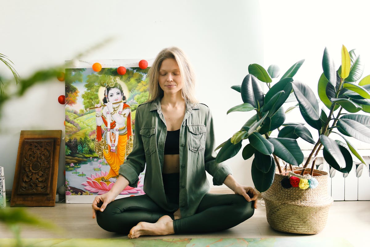 Mulher sentada no chão de olhos fechados praticando meditação em casa