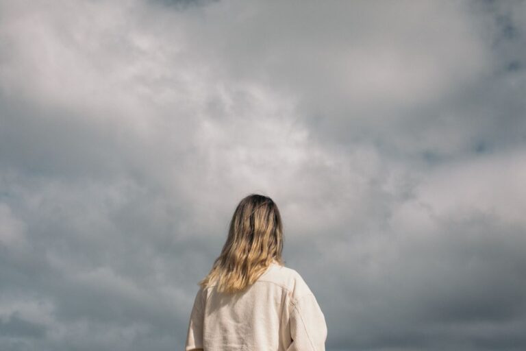 Mulher observando o céu ao pôr do sol em momento de contemplação e gratidão