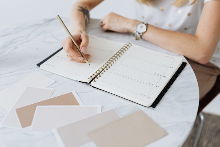 Mulher escrevendo e planejando suas metas em um planner sobre a mesa