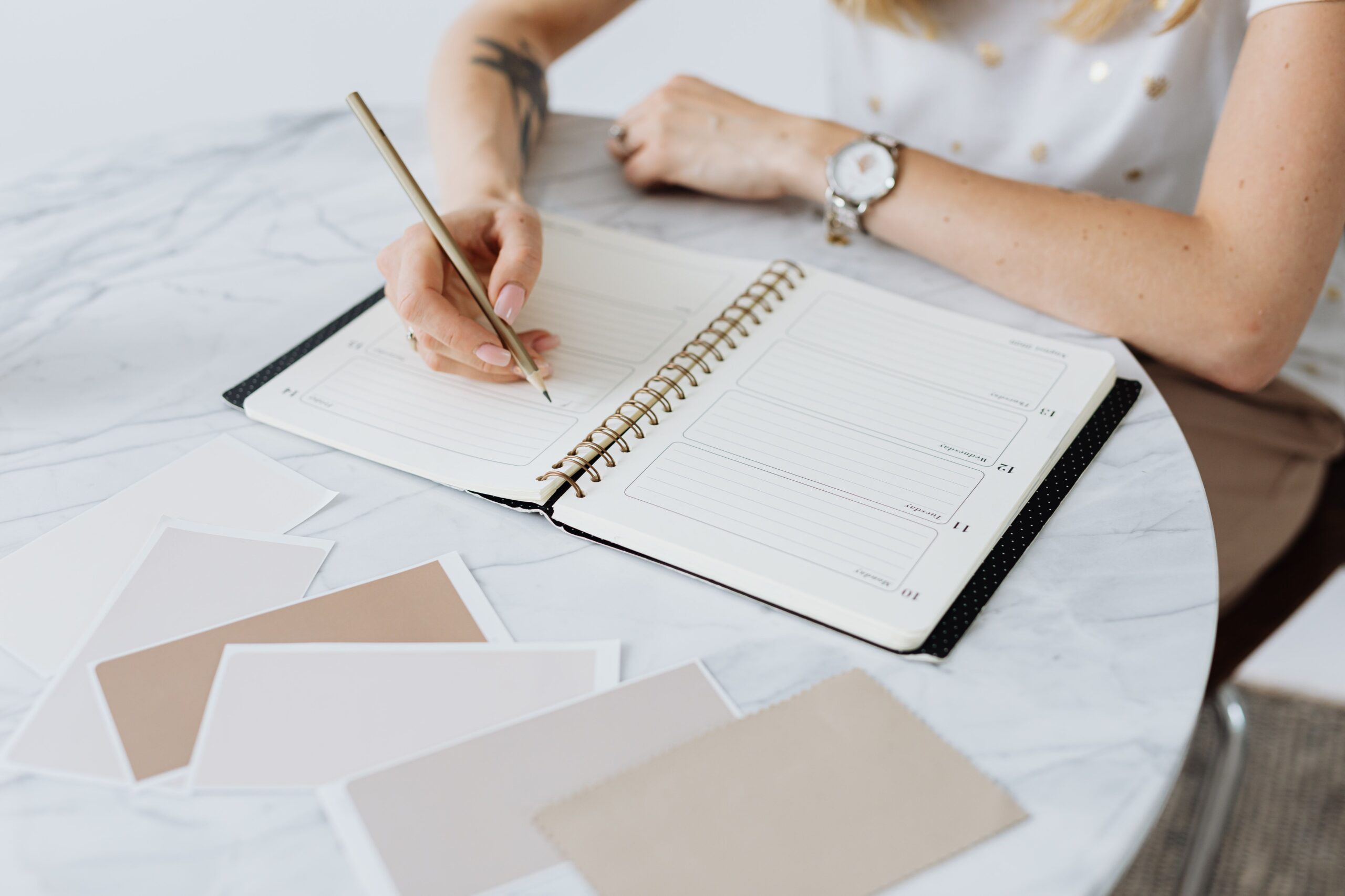 Mulher escrevendo e planejando suas metas em um planner sobre a mesa