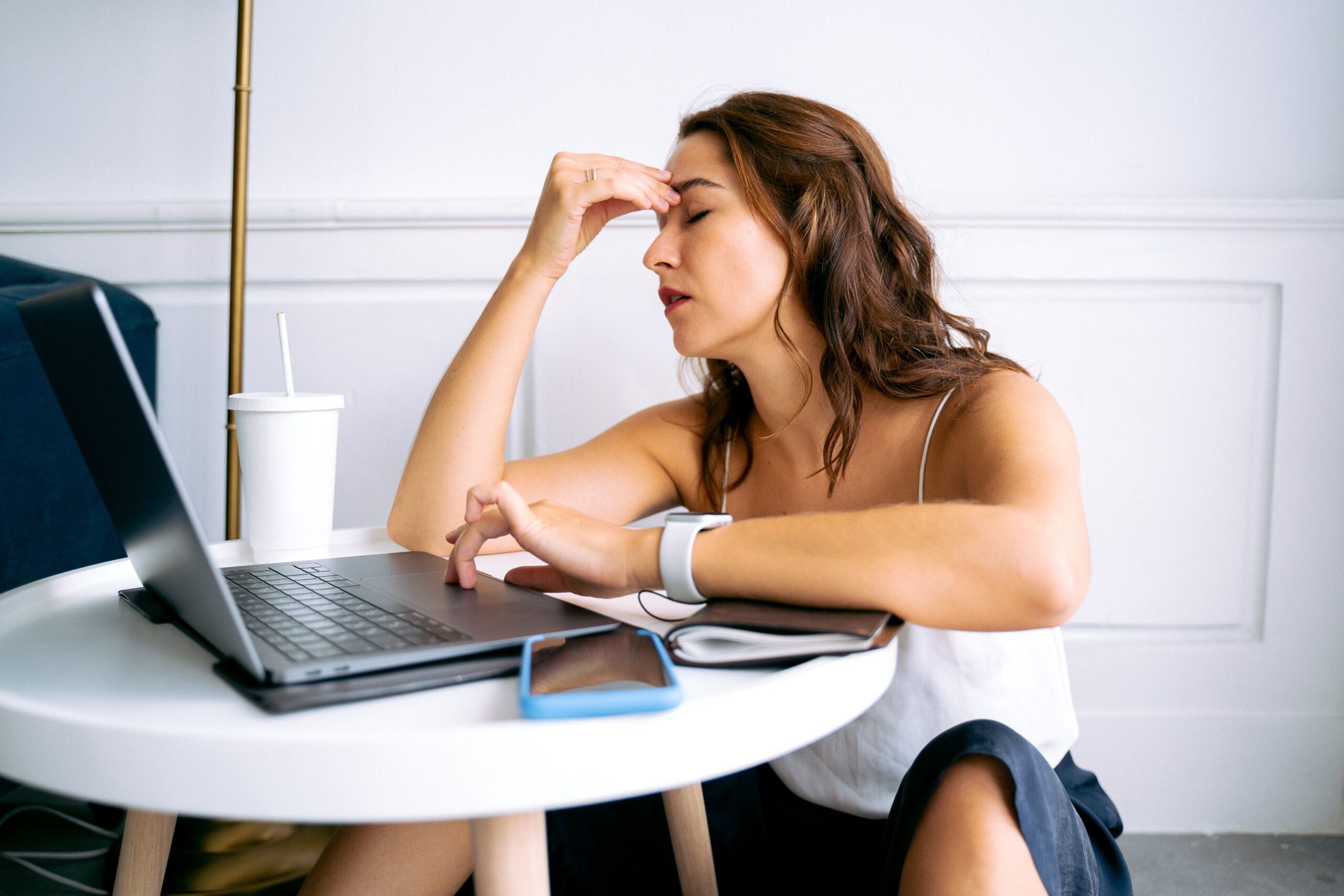 Mulher demonstrando cansaço e sobrecarga diante do laptop, sinal de desequilíbrio entre trabalho e vida