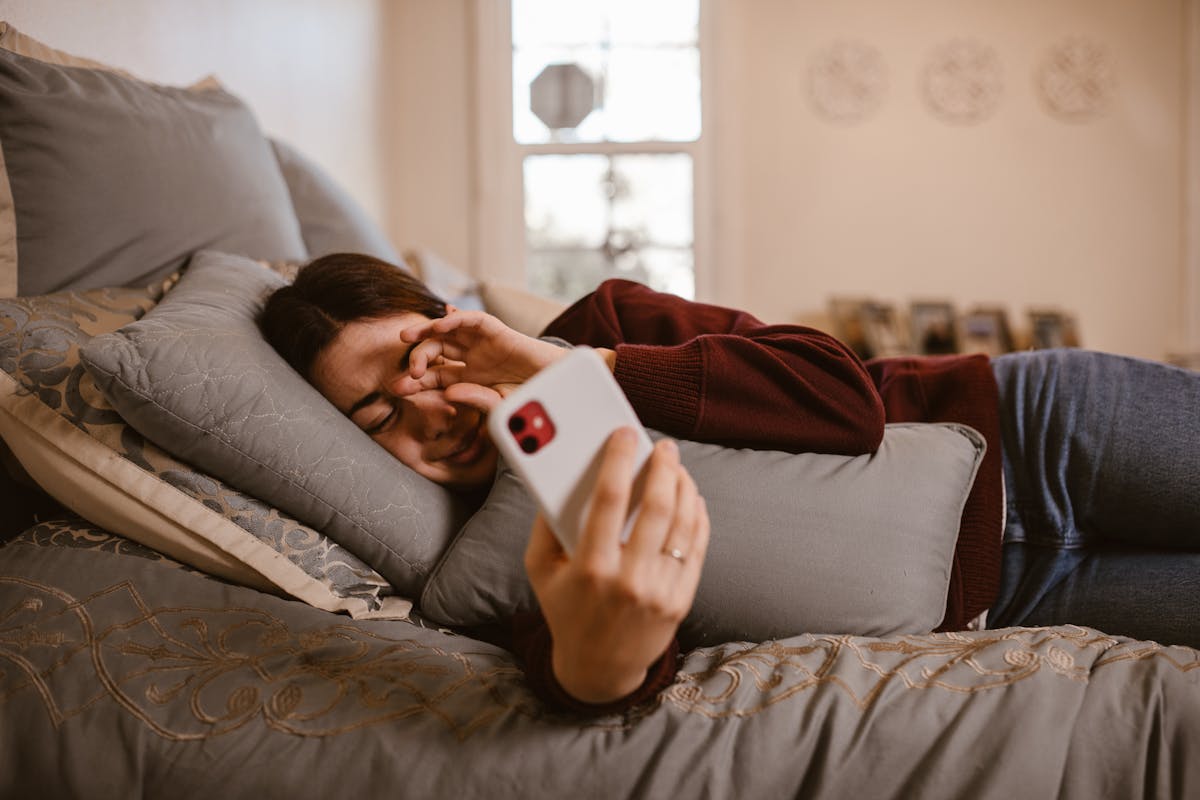 Mulher deitada na cama usando o smartphone à noite