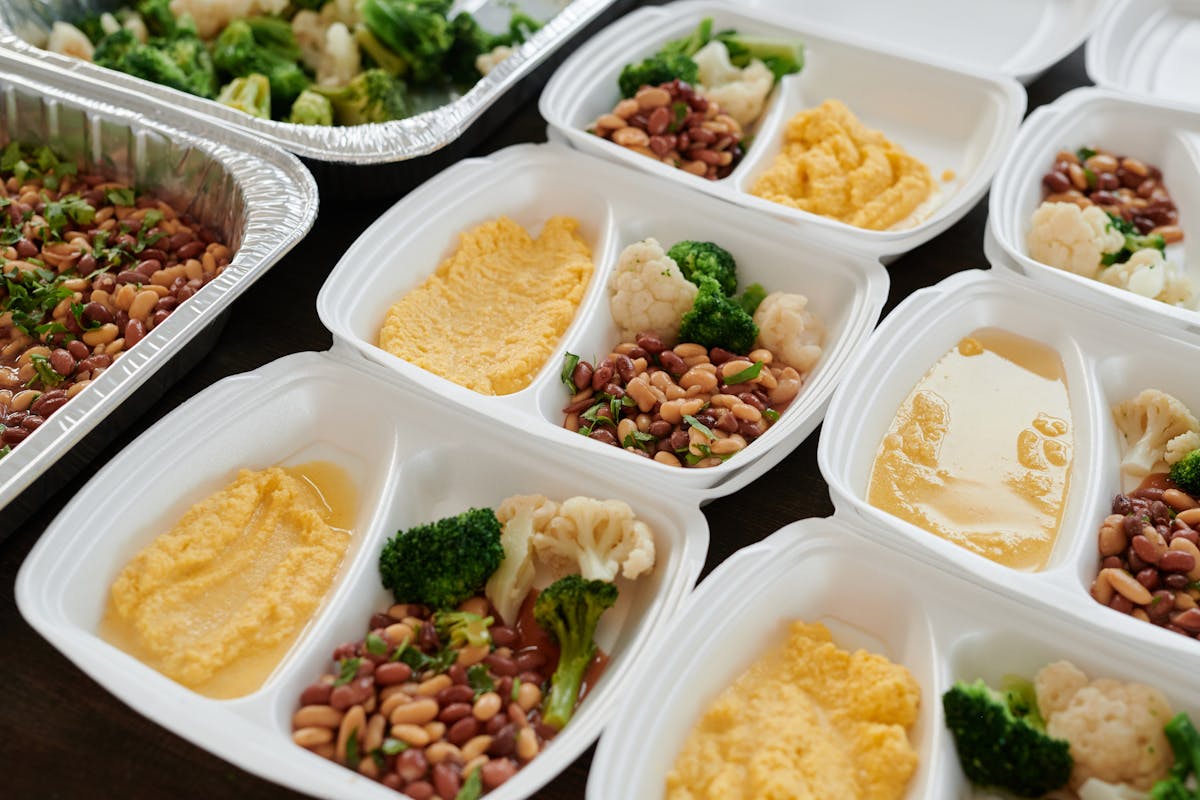 Potes de meal prep com porções de proteína, vegetais e carboidratos organizados