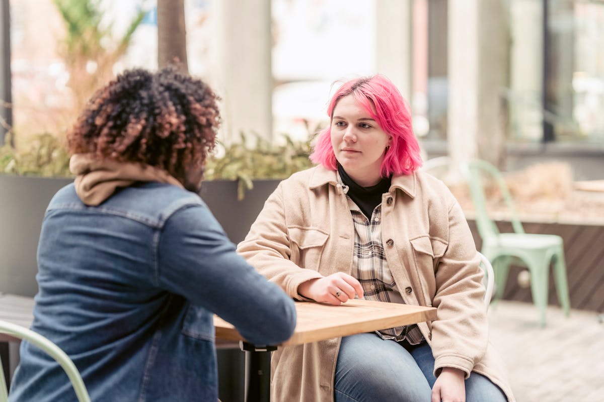 Pessoas conversando sentadas à mesa de um café, demonstrando apoio e conexão