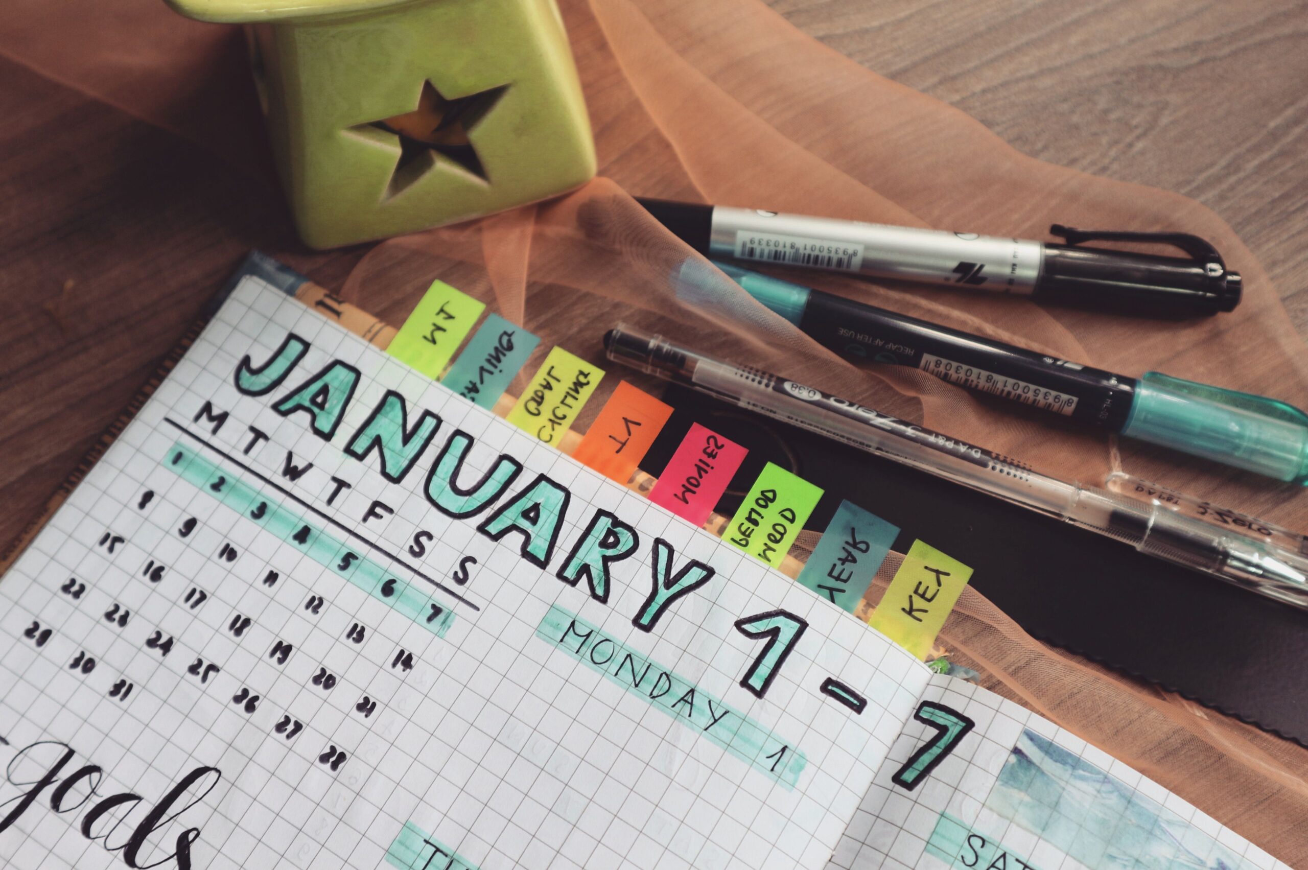 Planner aberto com metas e objetivos organizados por abas coloridas sobre a mesa