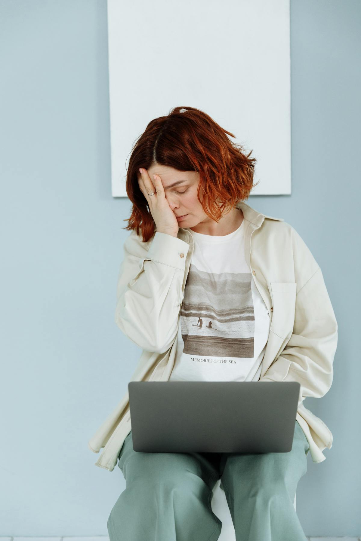 Mulher demonstrando estresse e cansaço enquanto trabalha com o notebook