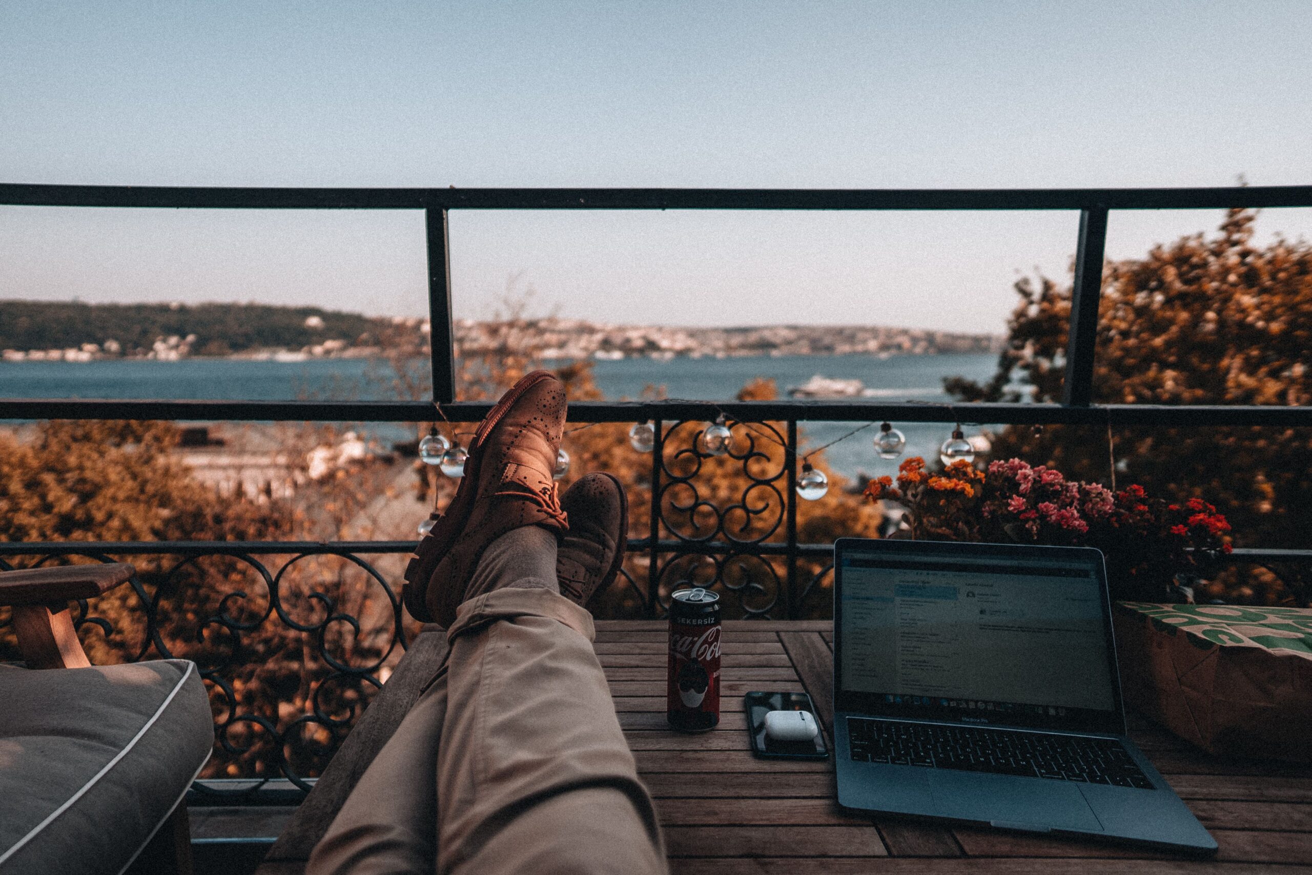 Pessoa relaxando em uma varanda tranquila, representando equilíbrio entre trabalho e descanso
