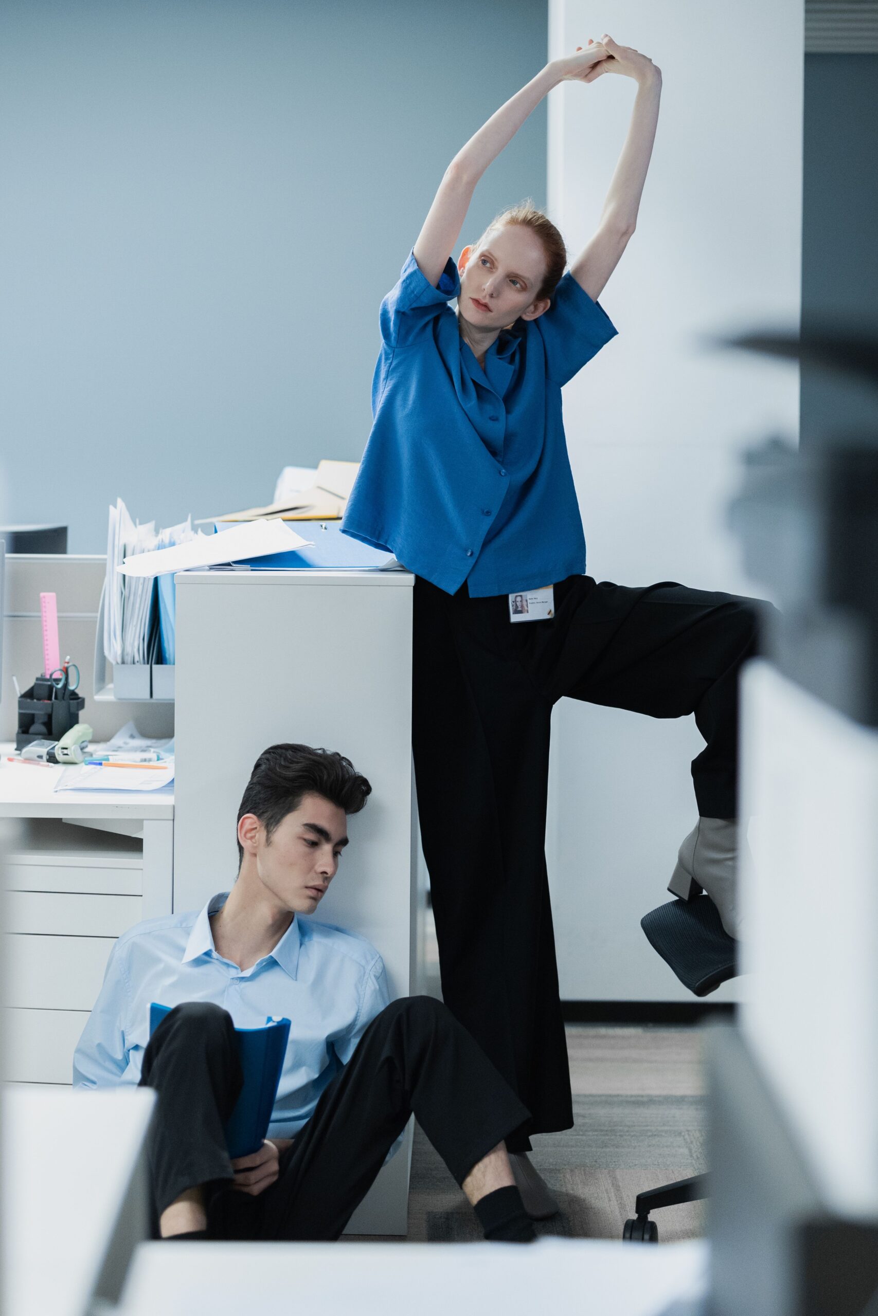 Dois colegas de trabalho fazendo uma pausa para alongar e se movimentar no escritório