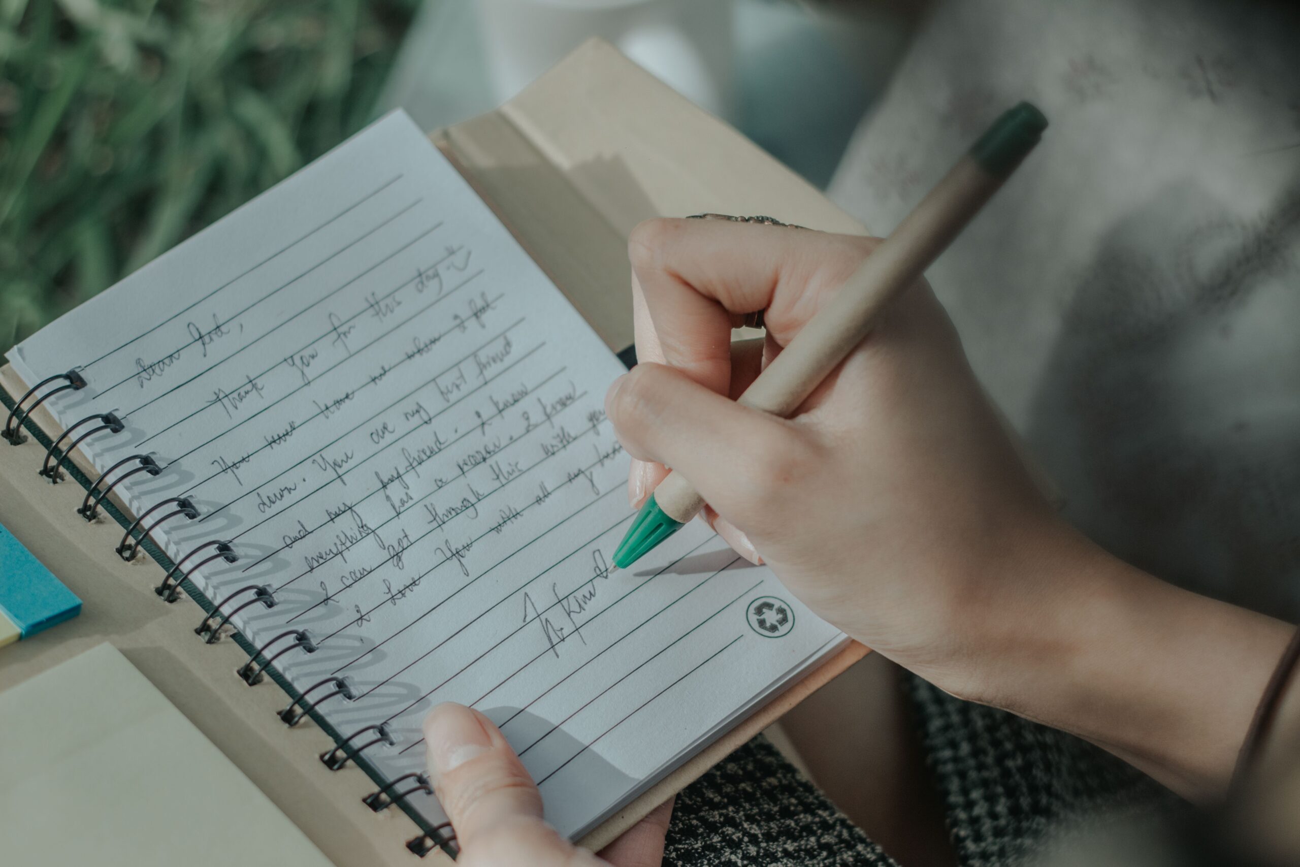 Mãos escrevendo anotações pessoais em um caderno aberto