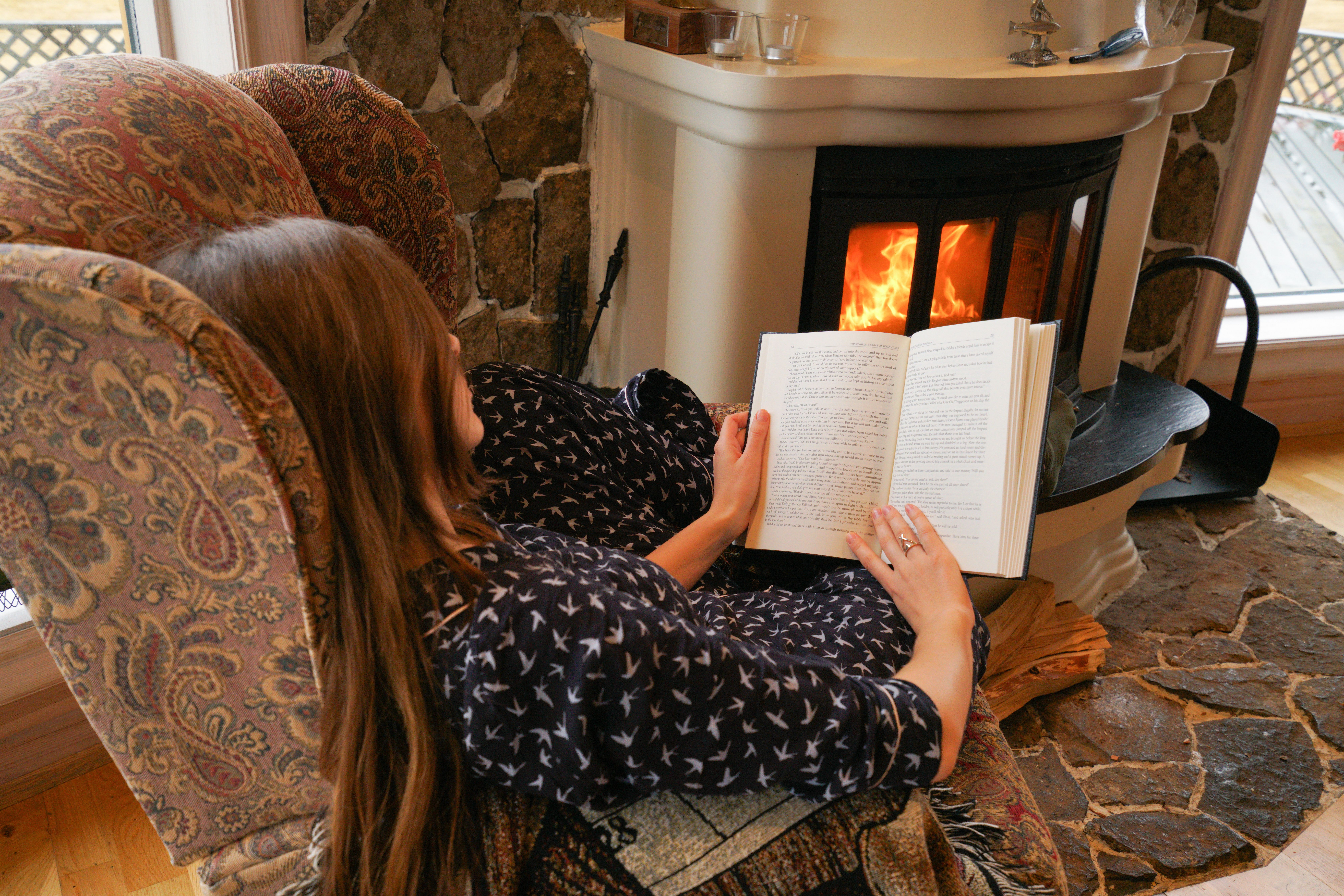 Mulher lendo um livro em uma poltrona sob luz baixa e acolhedora