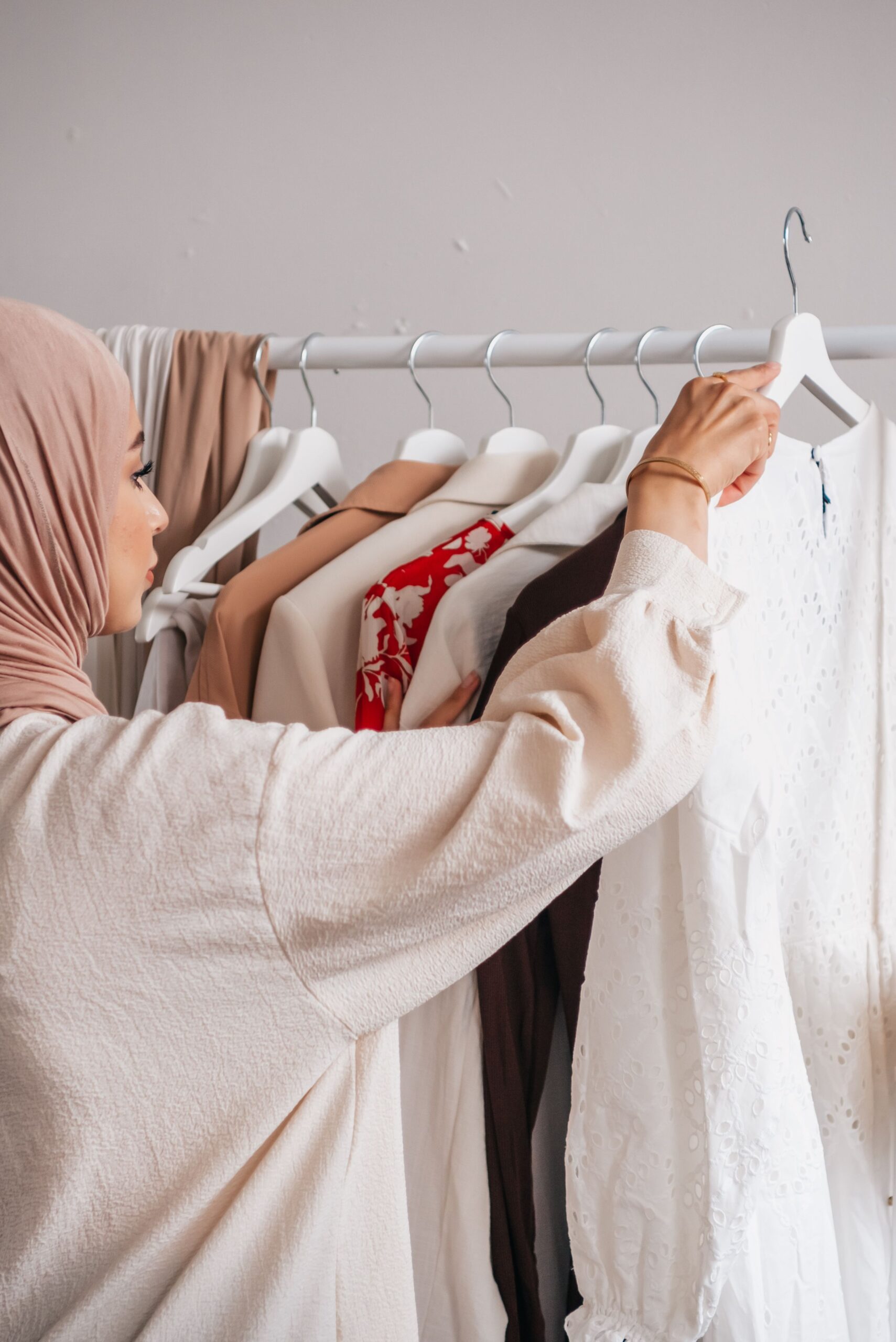 Mulher em dúvida escolhendo uma peça de roupa entre várias opções