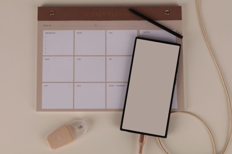 Planner semanal aberto sobre uma mesa com caneta e celular