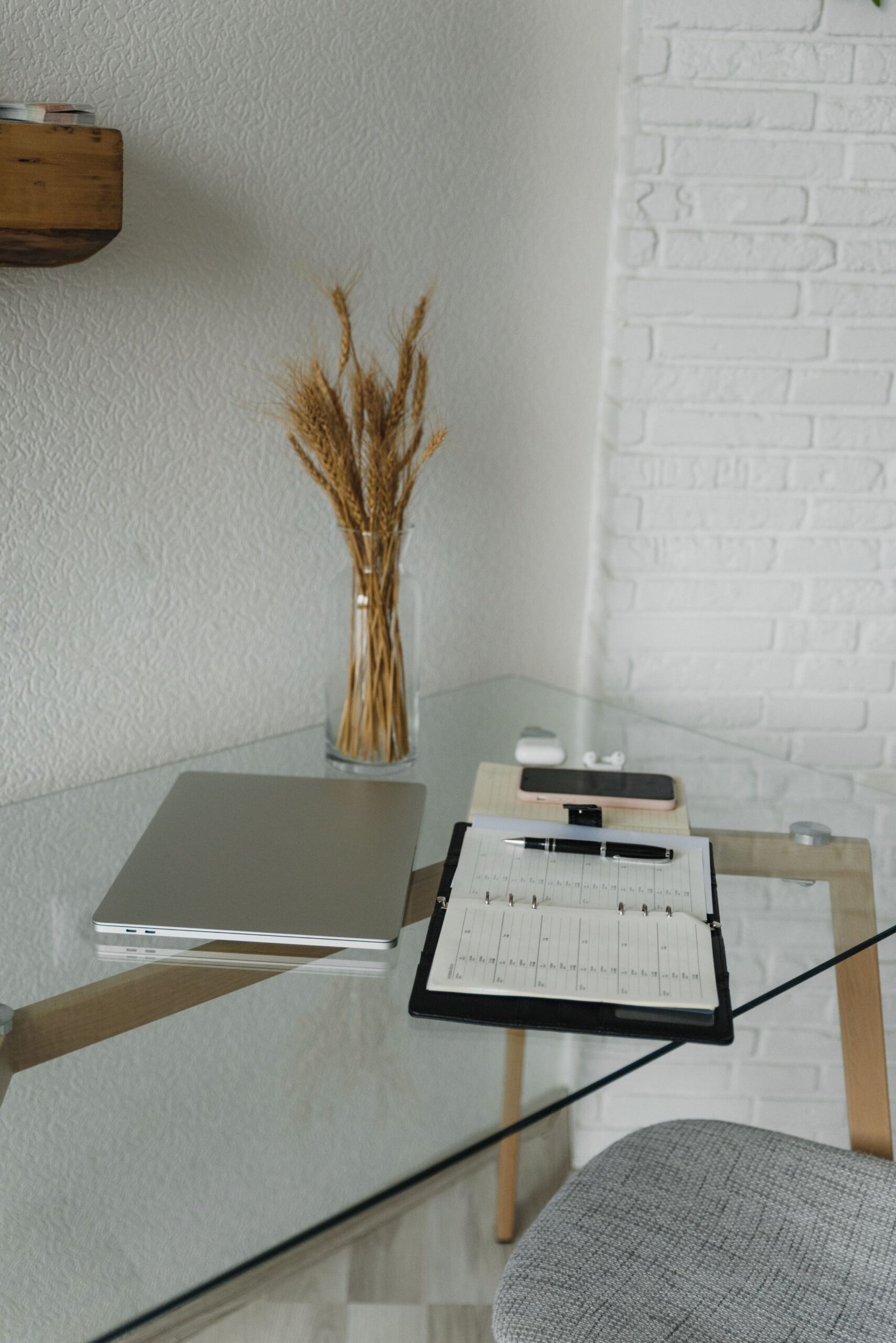 Caderno aberto com caneta ao lado de um notebook na mesa