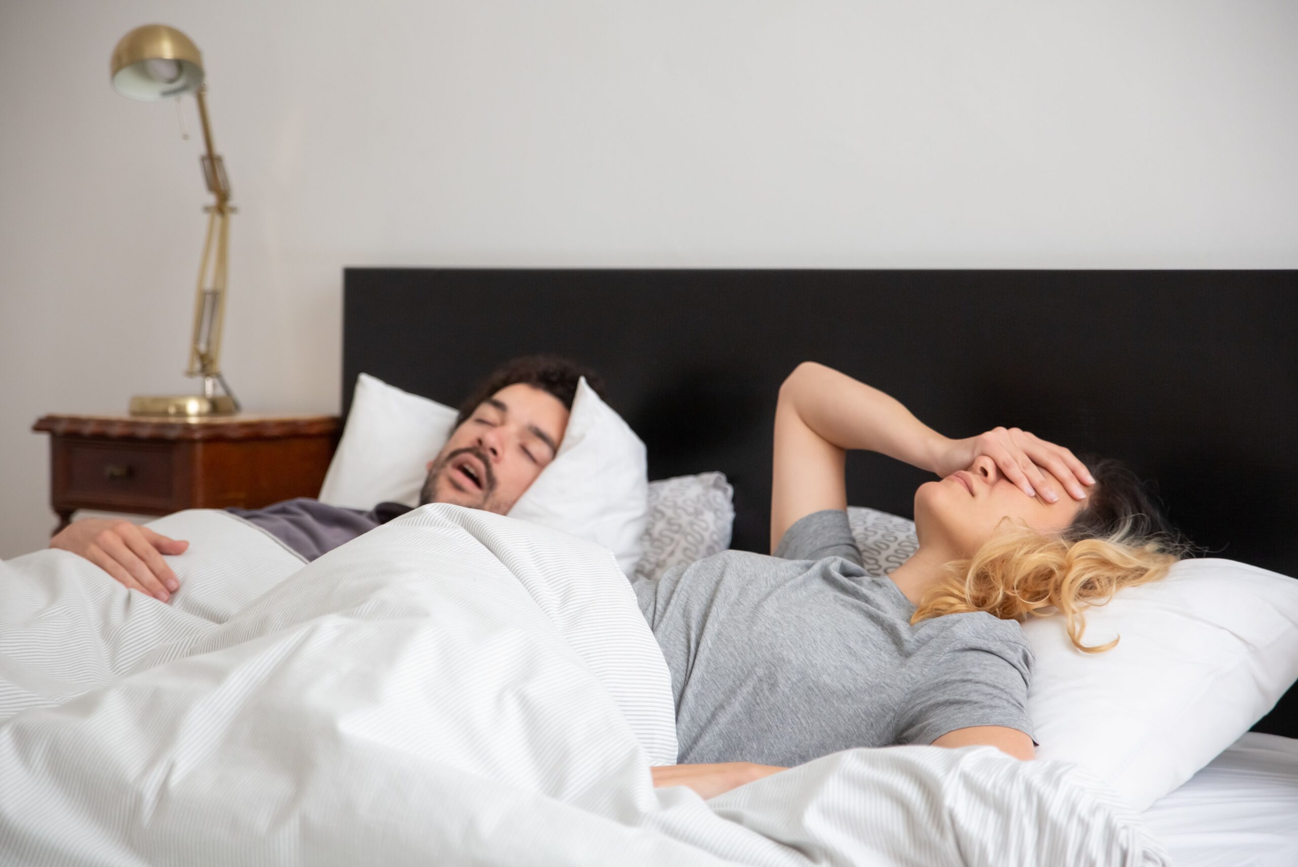 Homem dormindo ao lado de uma mulher na cama durante a noite